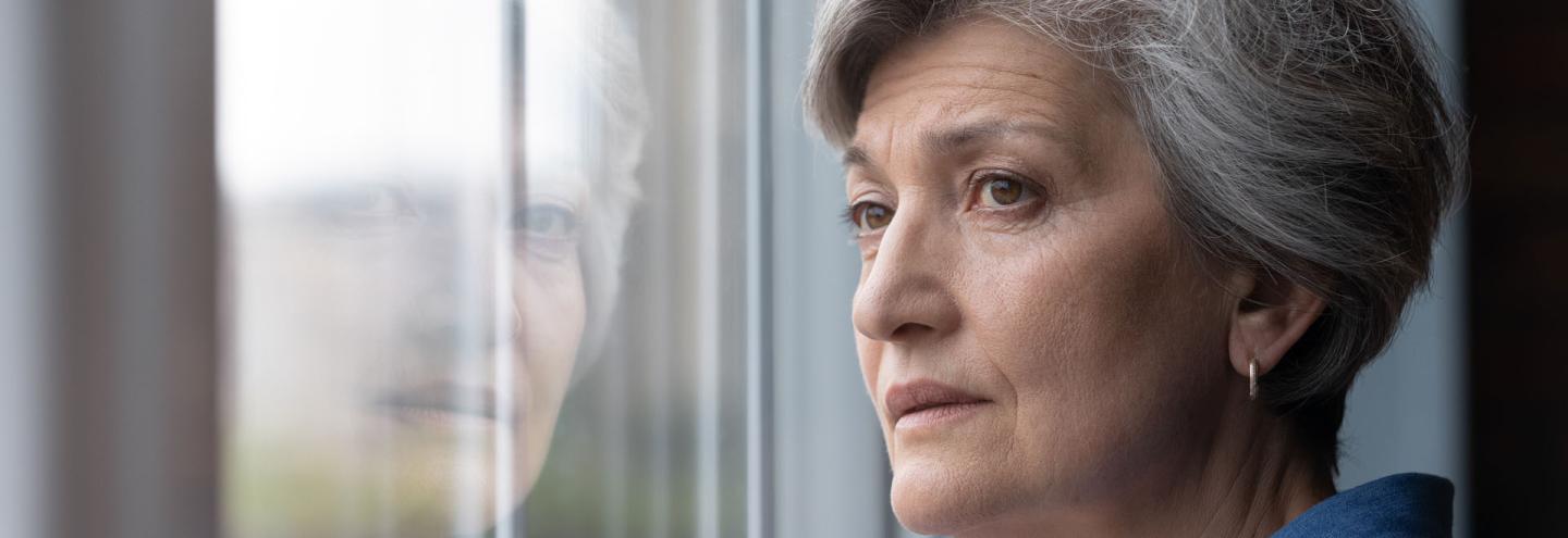 Veuve de 60 ans qui regarde par la fenêtre