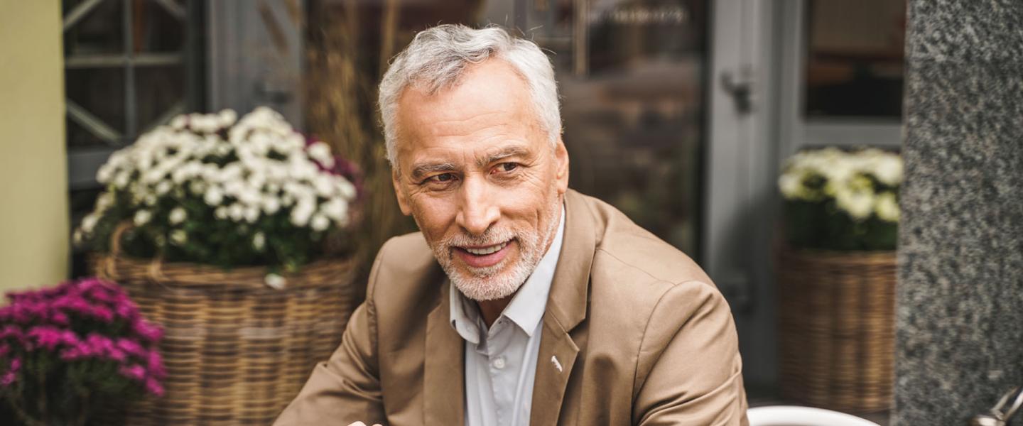 Homme de 60 ans discutant de sa retraite à la terrasse d'un café